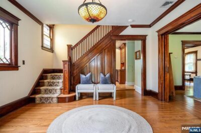 Elegant foyer with a wood staircase, original millwork, hardwood floors, and stained glass windows.