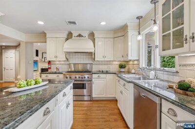 Updated kitchen blending classic architectural details with white cabinetry, granite countertops, stainless steel appliances, and hardwood floors.