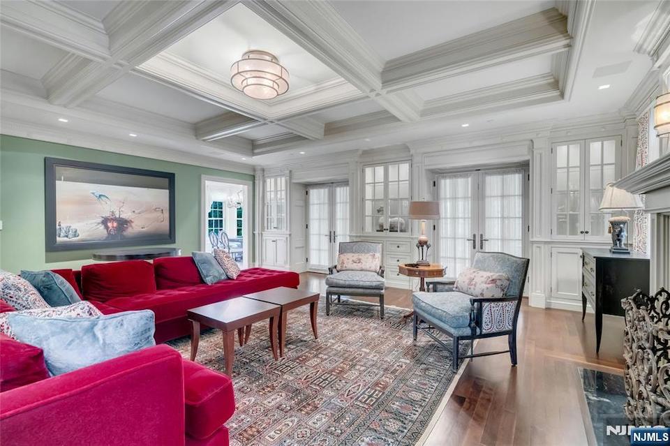 Spacious living room with coffered ceilings, built-in cabinetry, hardwood floors, and a traditional open layout.